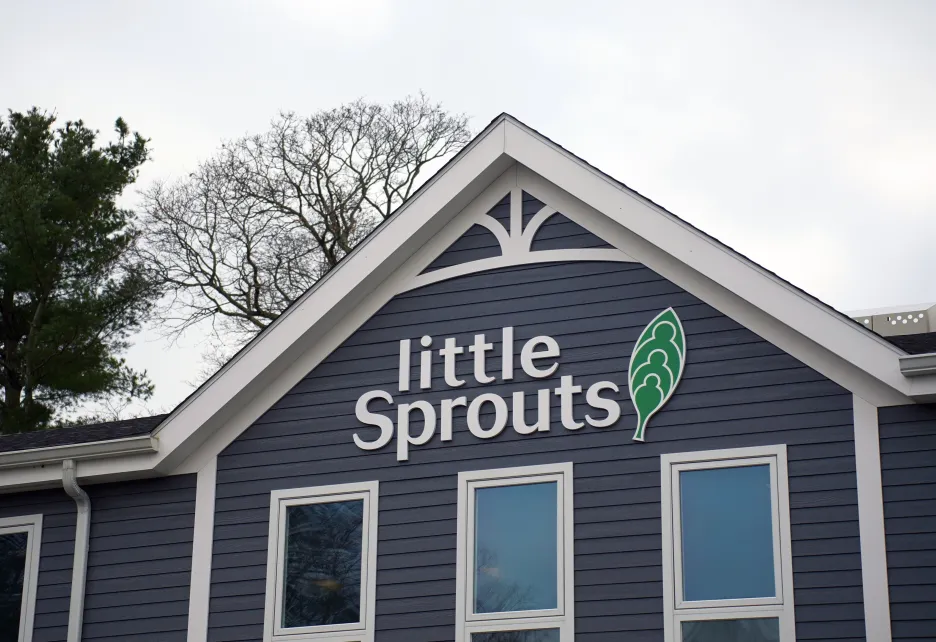 Little Sprouts logo on a gray building with white trim along the windows and roof