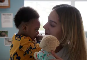 Teacher holding a baby and stuffed animal 