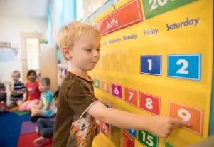 Preschooler using a giant colorful calendar