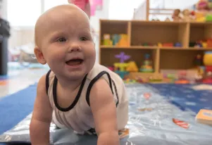Infant Crawling on a light blue play mat  