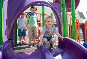 Three toddlers at the top of purple side by side slide