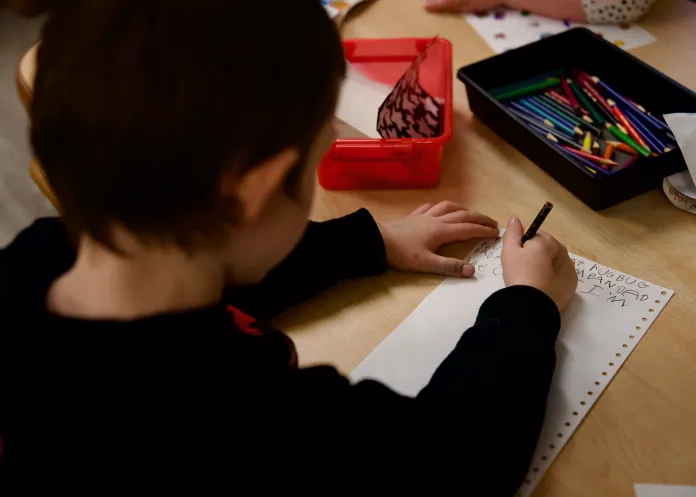 Child practicing their writing at a wooden table