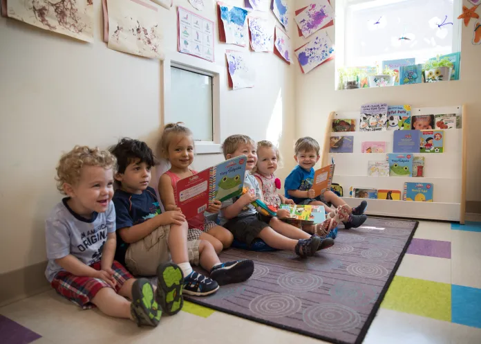 Six kids sitting together reading in the classrooms reading corner