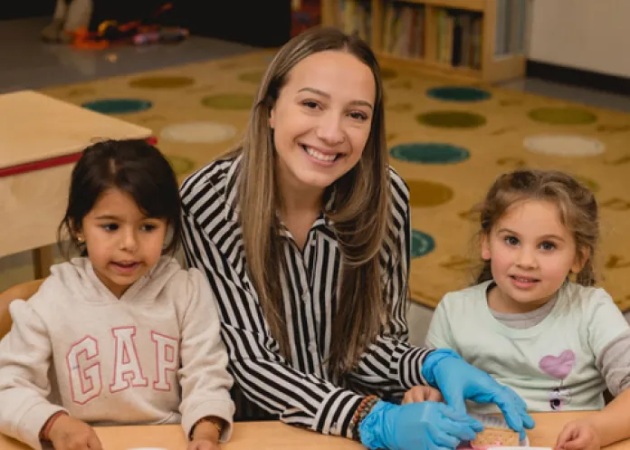 Teacher giving snacks to two children sitting at a table