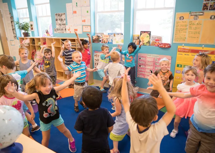 Preschool students dancing around the classroom