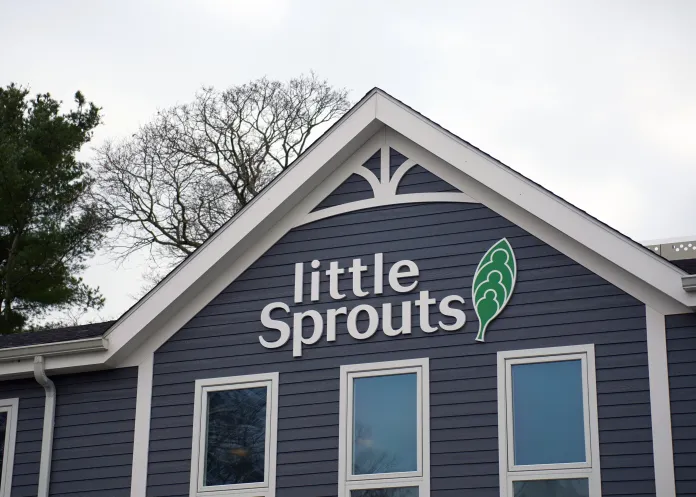 Little Sprouts logo on a gray building with white trim along the windows and roof