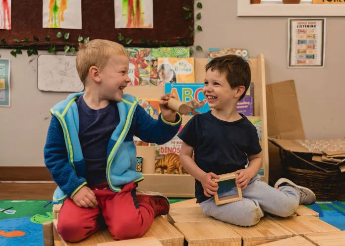 Two happy Little Sprouts children playing with wooden blocks