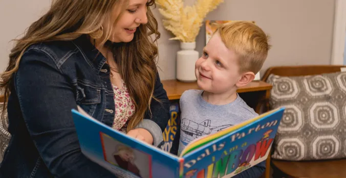 A teacher and student reading I Am a Rainbow by Dolly Parton 