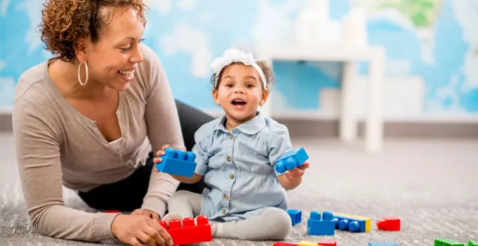 Parent and toddler smiling while playing with colorful building blocks